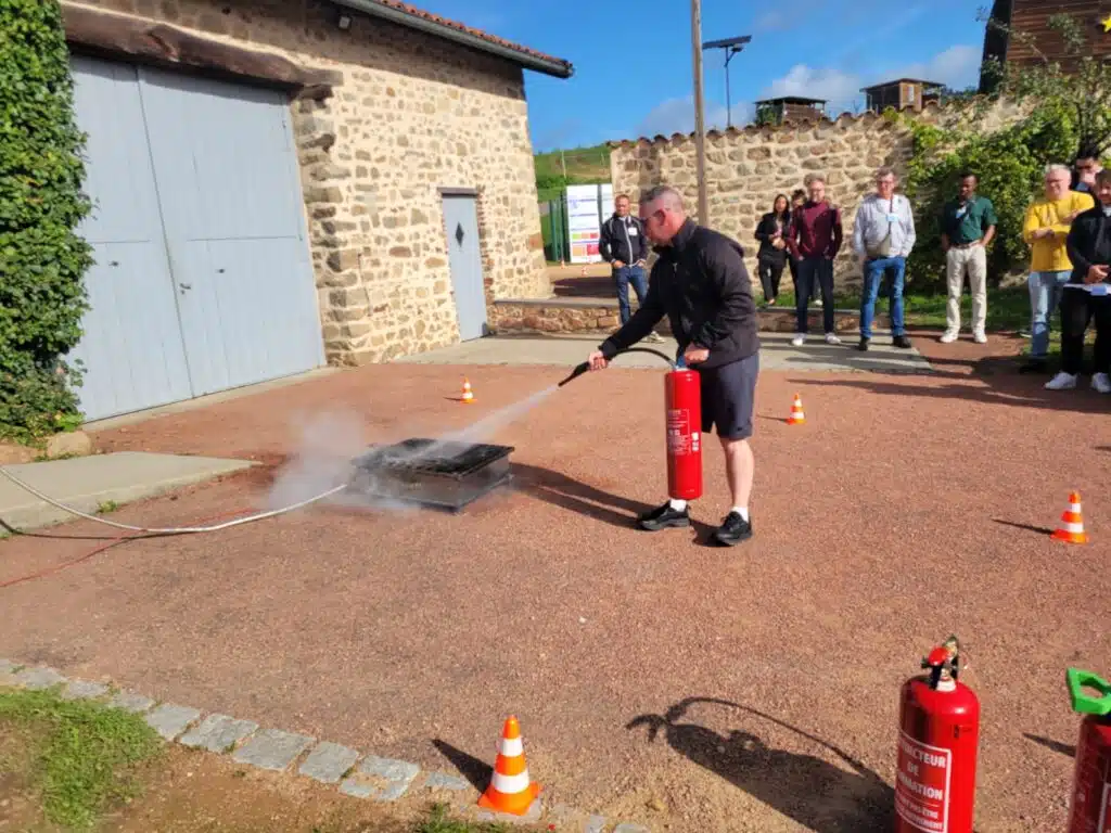Participant utilisant un extincteur sur un départ de feu simulé pendant un atelier pratique