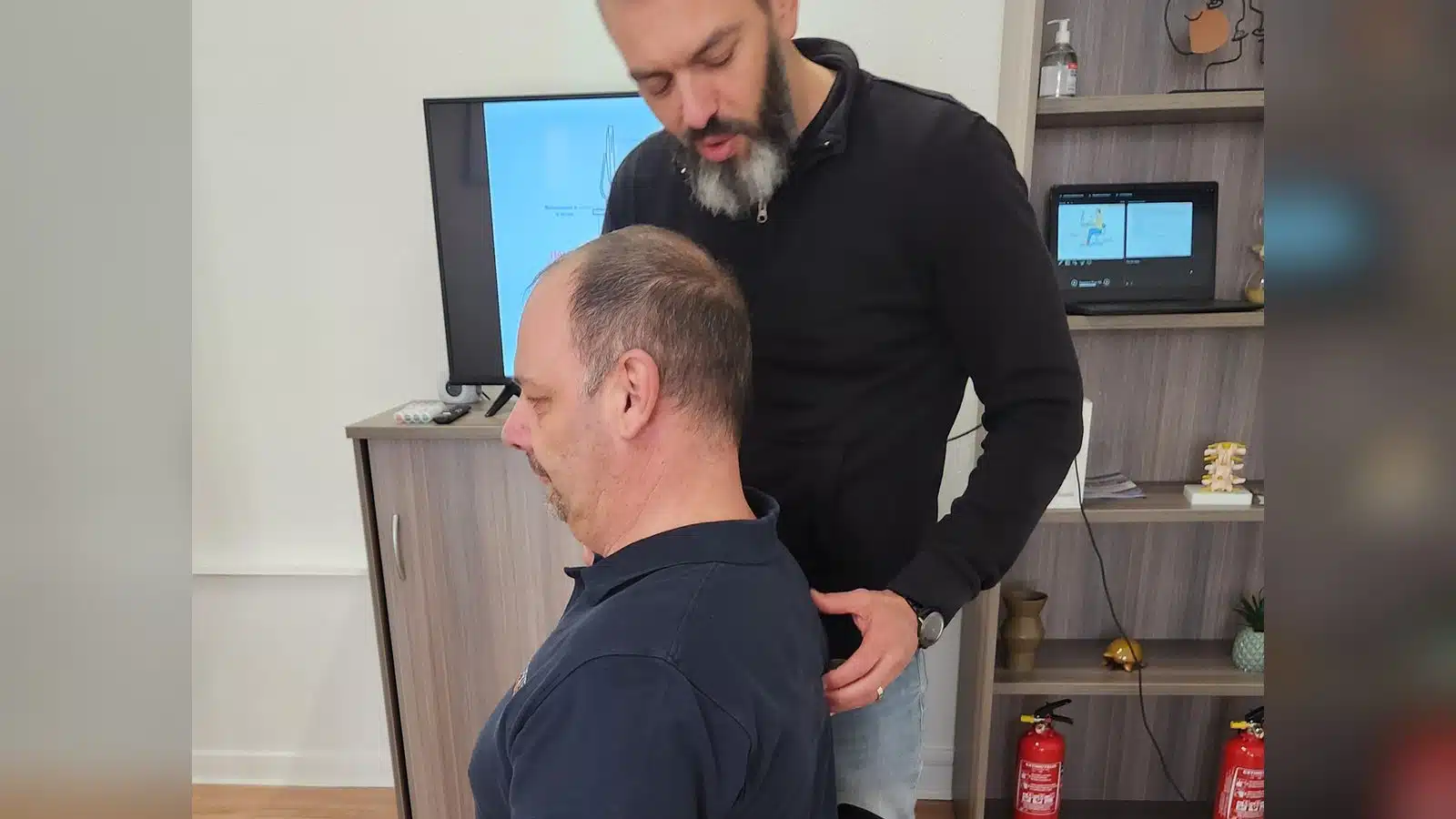 Formateur corrigeant la posture assise d'un participant lors d'un atelier gestes et postures